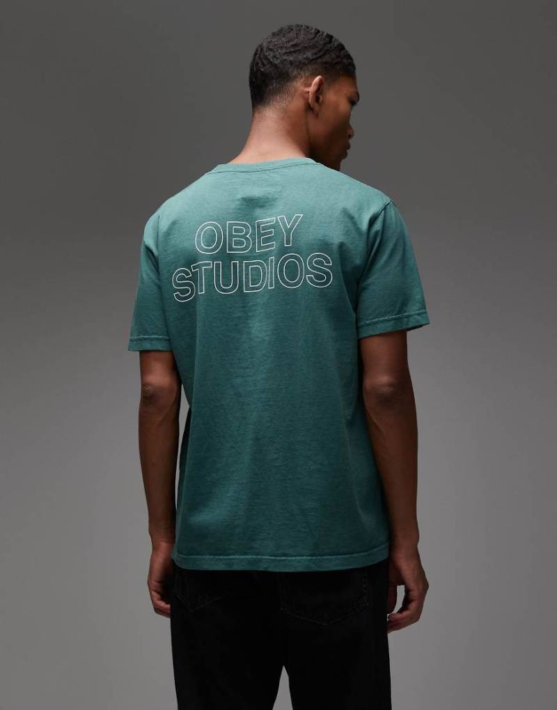 Obey - T-Shirt in Grün mit „Obey Studios"-Rahmenschriftzug mit Rückenprint von Obey