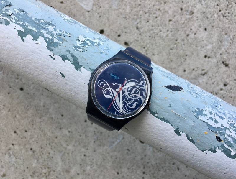 Tristan Blaue Flexy-Uhr Mit Einem Verschnörkten Silber-Design Im Gesicht Swatch Tristan Blaue Flexy-Uhr Mit Einem Verschnörkten Silber-Design Im Gesicht Swatch von Omnimonger