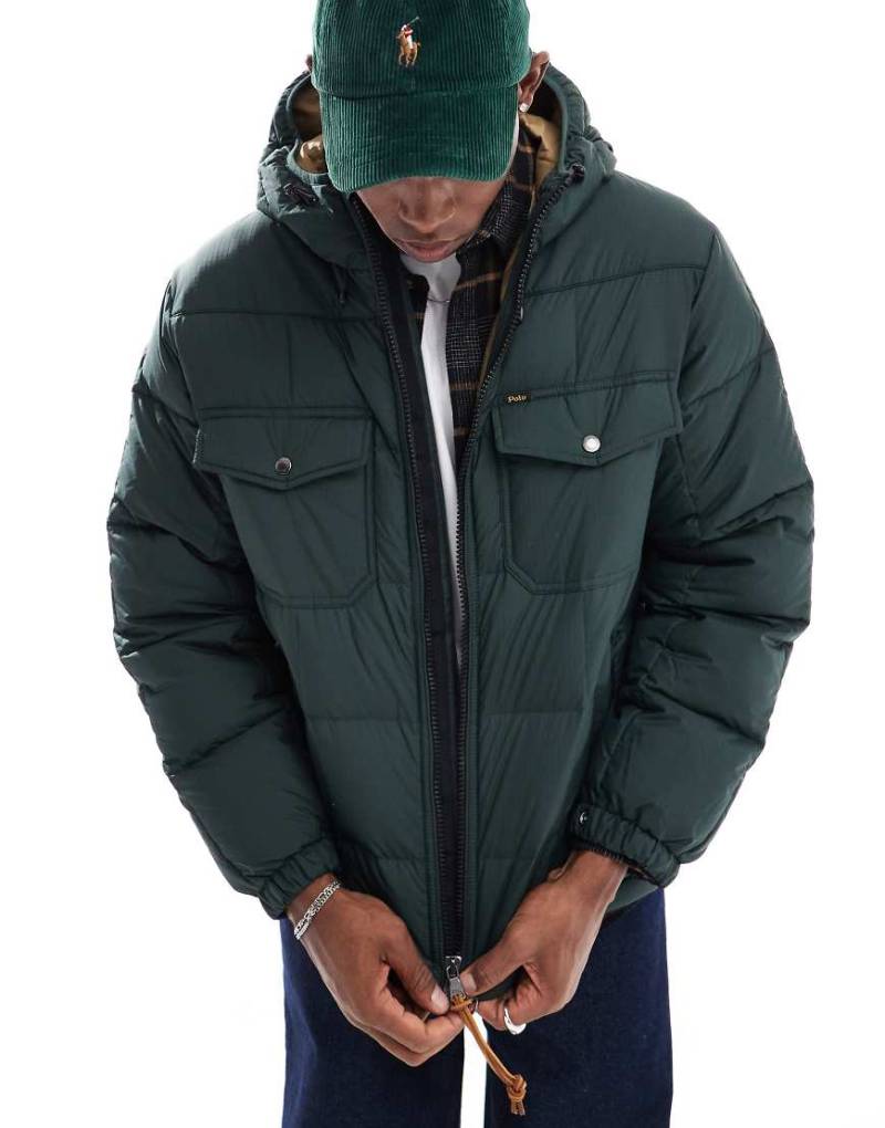 Polo Ralph Lauren - Utility-Pufferjacke in Dunkelgrün mit Kapuze und Daunenfüllung Polo Ralph Lauren - Utility-Pufferjacke in Dunkelgrün mit Kapuze und Daunenfüllung von Polo Ralph Lauren