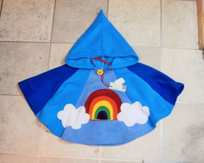 Regenbogen Fleece Kinder Poncho Wolkentaschen, Handgemachter Fimoknopf Regenbogen Fleece Kinder Poncho Wolkentaschen, Handgemachter Fimoknopf von RaggtaggPixie