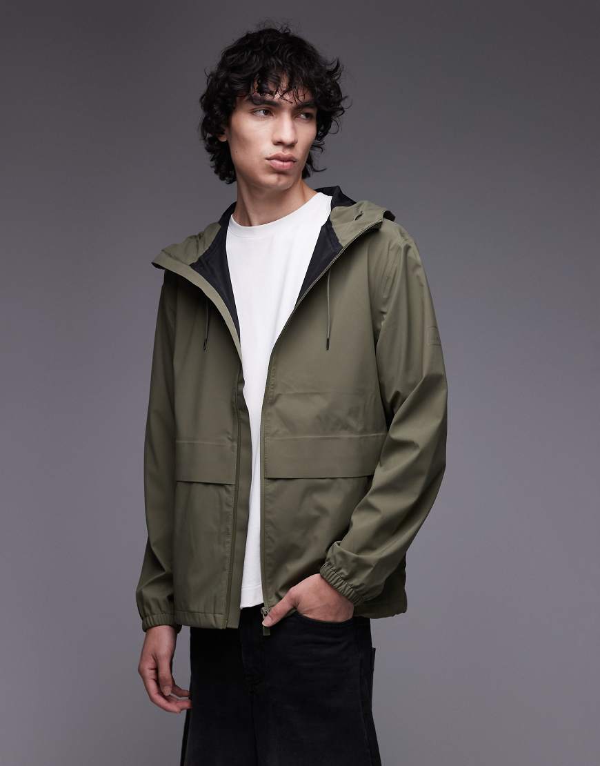 Rains - 12420 Suva - Wasserdichte Hardshell-Jacke in Khaki mit Reißverschluss-Grün Rains - 12420 Suva - Wasserdichte Hardshell-Jacke in Khaki mit Reißverschluss-Grün von Rains