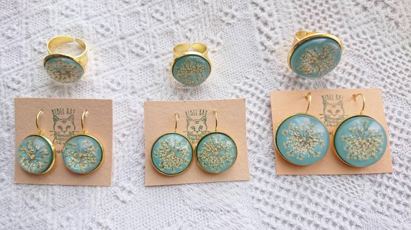 Wilde Weißblumen Handgemachte Epoxy Ohrringe & Ringe in Einem Goldenen Rahmen Pastelltürkisem Hintergrund Wilde Weißblumen Handgemachte Epoxy Ohrringe & Ringe in Einem Goldenen Rahmen Pastelltürkisem Hintergrund von RebelKatArt