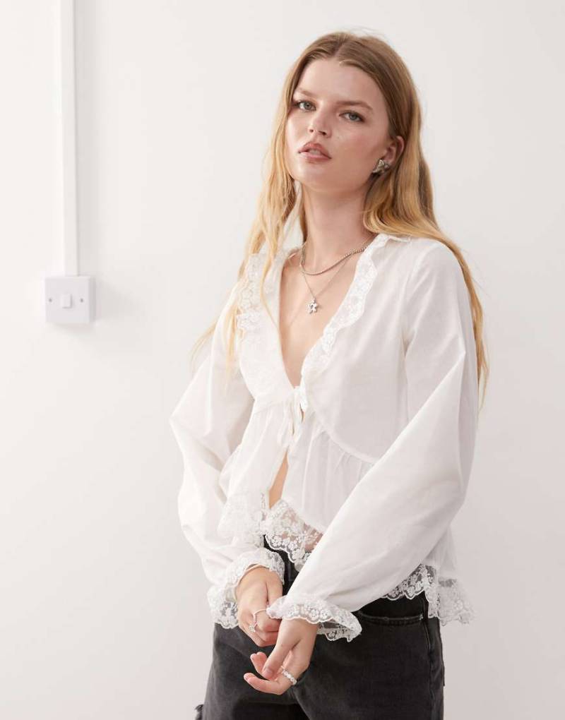 Reclaimed Vintage - Bluse in Elfenbeinweiß mit Spitzenbesatz und geschnürter Vorderseite von Reclaimed Vintage