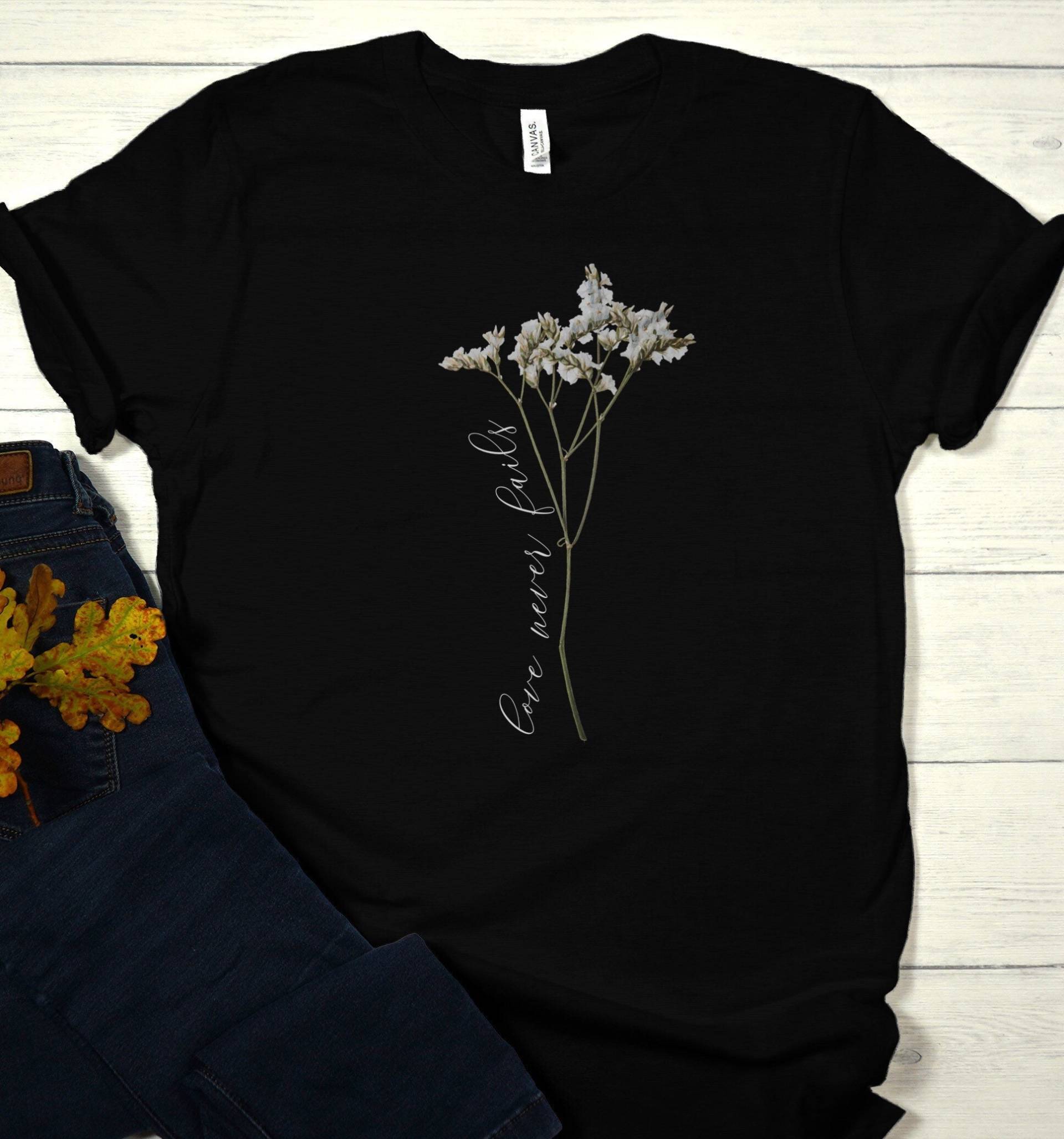 Love Never Fails Christliche Bibel Vers Blume T-Shirt von RootedInChristStudio