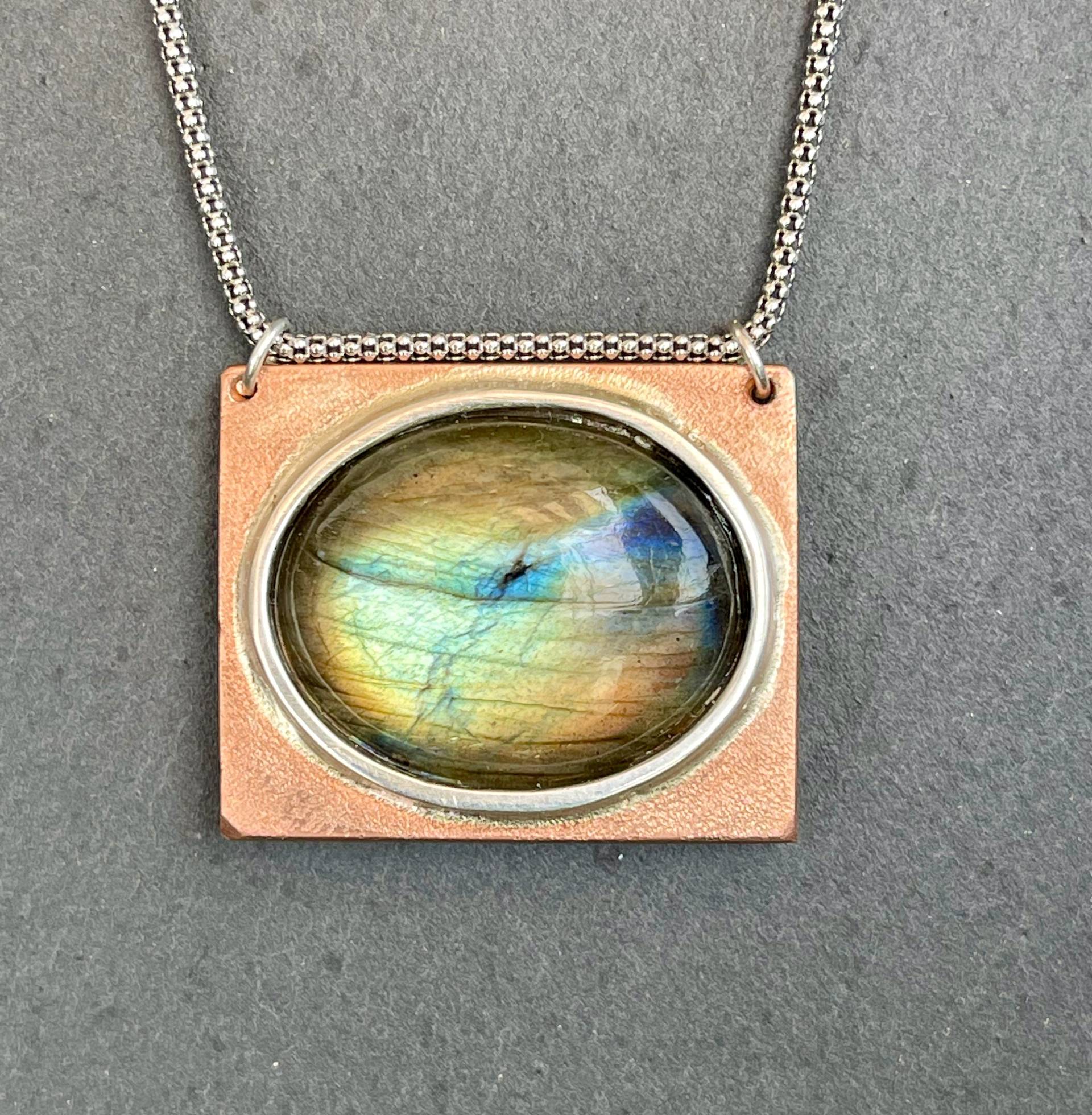 Duett Ein Farbenfroh Schimmernder Labradorit-Anhänger - Aus Kupfer Und 925 Silber Ziert Das Relief Eines Labradors von SchmuckundSteine