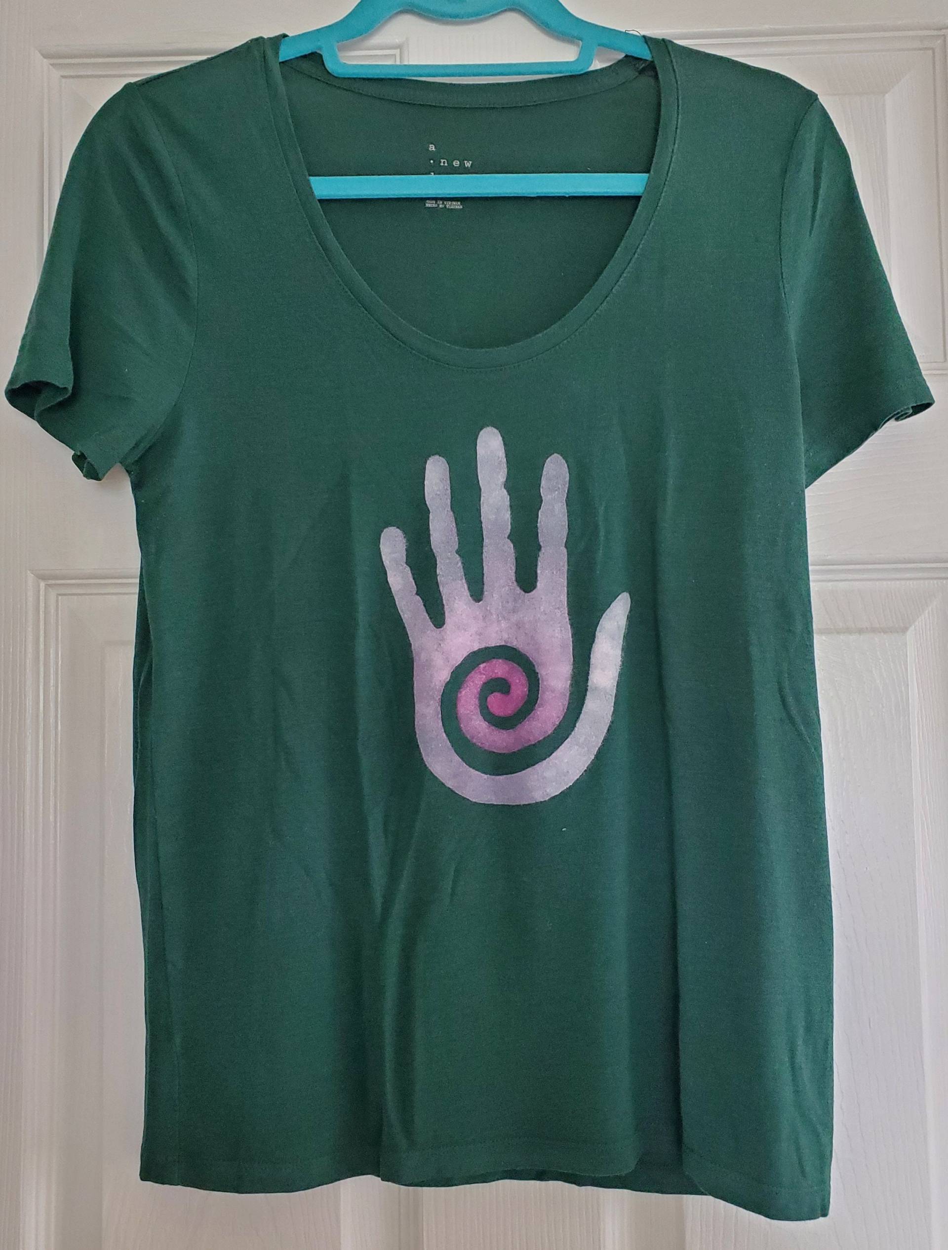 Kurzärmeliges Grünes Handbemaltes T-Shirt Mit Hopi Healer Hand Design Kurzärmeliges Grünes Handbemaltes T-Shirt Mit Hopi Healer Hand Design von StringLilyCreations