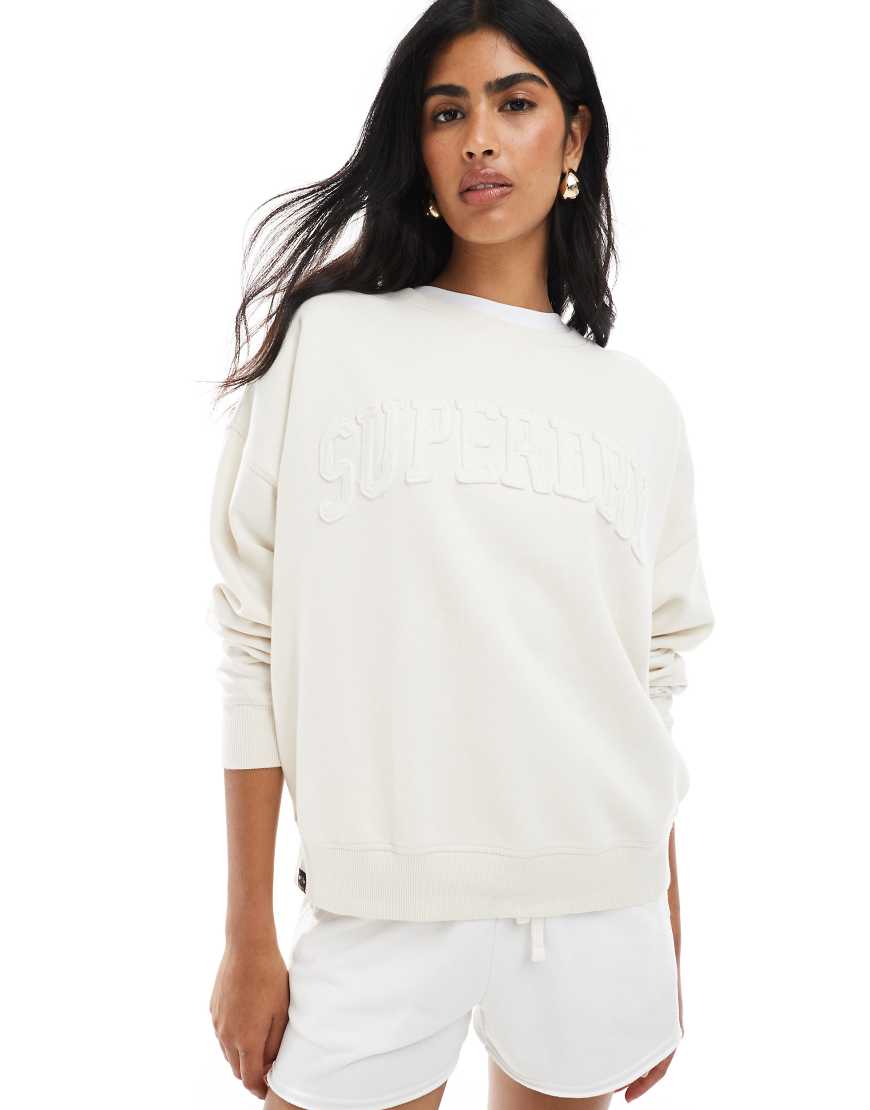Superdry - Athletic - Basic-Sweatshirt in Wüstenknochen-Wollweiß mit gleichfarbiger Applikation und Rundhalsausschnitt Superdry - Athletic - Basic-Sweatshirt in Wüstenknochen-Wollweiß mit gleichfarbiger Applikation und Rundhalsausschnitt von Superdry
