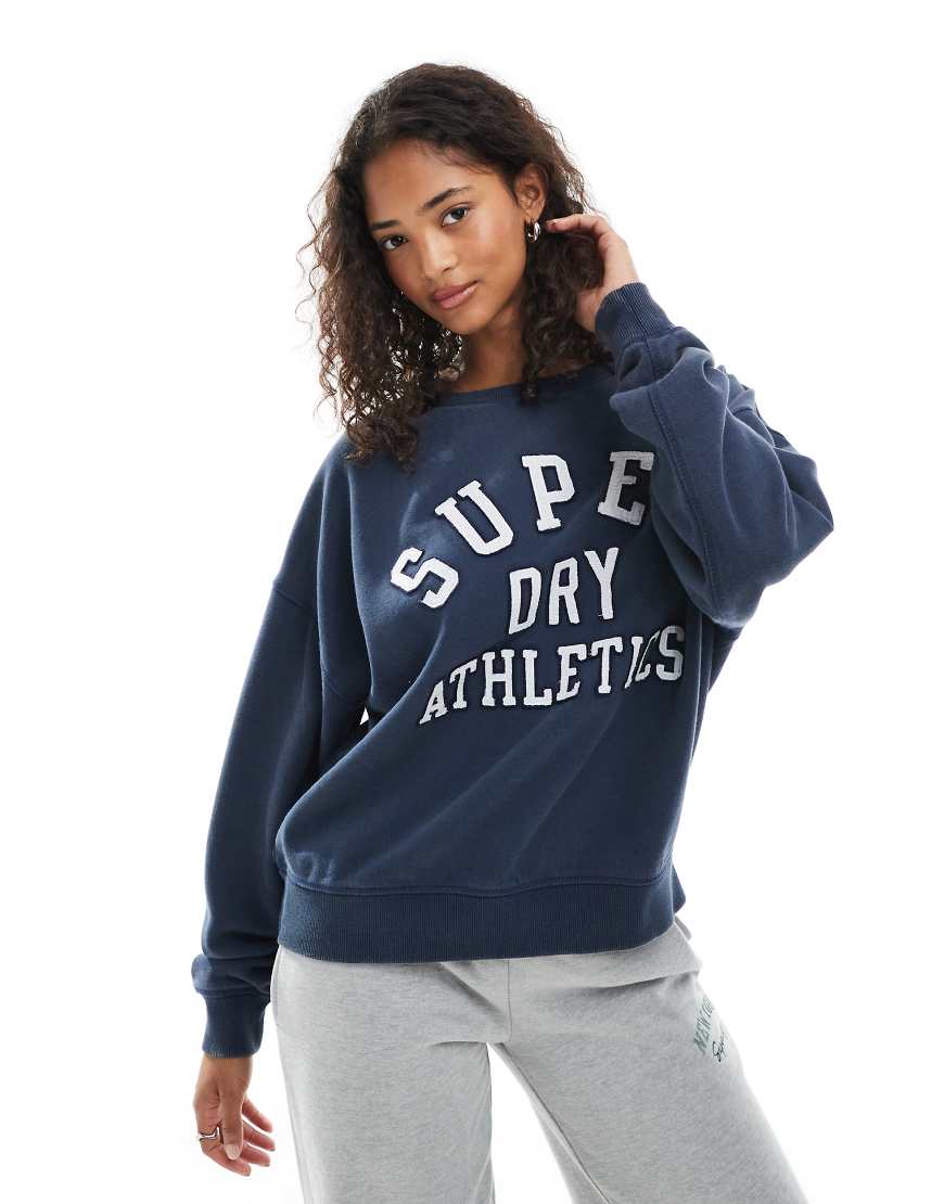 Superdry - Athletic Essentials - Relaxed Fit Sweatshirt in kräftigem Marineblau mit Applikation Superdry - Athletic Essentials - Relaxed Fit Sweatshirt in kräftigem Marineblau mit Applikation von Superdry