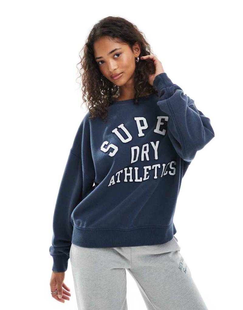 Superdry - Athletic Essentials - Relaxed Fit Sweatshirt in kräftigem Marineblau mit Applikation Superdry - Athletic Essentials - Relaxed Fit Sweatshirt in kräftigem Marineblau mit Applikation von Superdry