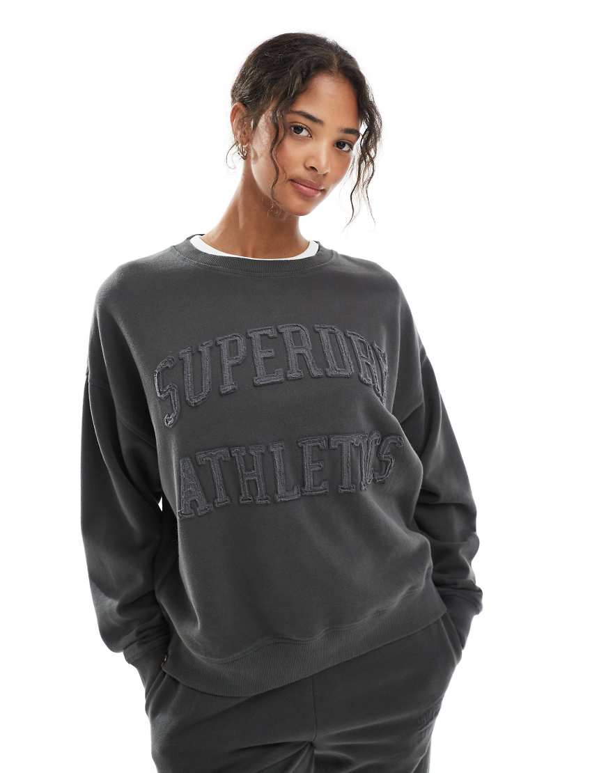Superdry - Athletic Essentials - Sweatshirt in Anthrazit mit Rundhalsausschnitt und farblich abgestimmter Applikation-Grau Superdry - Athletic Essentials - Sweatshirt in Anthrazit mit Rundhalsausschnitt und farblich abgestimmter Applikation-Grau von Superdry