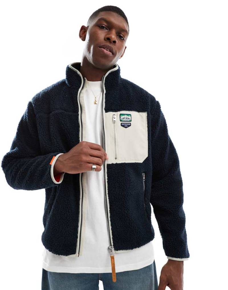 Superdry - Fleece-Jacke in Eclipse-Marineblau mit Reißverschluss in Vintage-Retrodesign Superdry - Fleece-Jacke in Eclipse-Marineblau mit Reißverschluss in Vintage-Retrodesign von Superdry