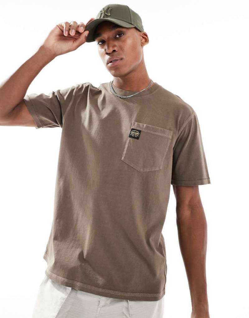 Superdry - T-Shirt in verwaschenem Morchelbraun mit Kontrastnaht und Brusttasche Superdry - T-Shirt in verwaschenem Morchelbraun mit Kontrastnaht und Brusttasche von Superdry