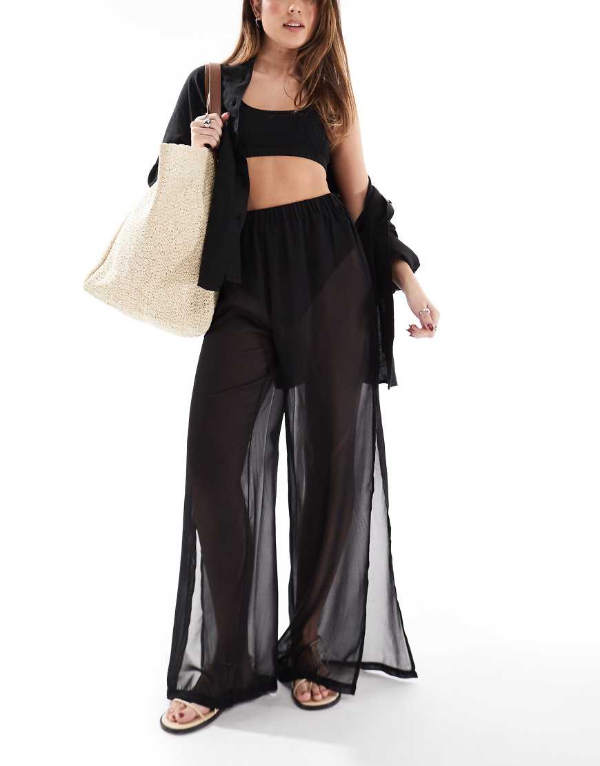 Threadbare - Weit geschnittene, transparente Strandhose in Schwarz mit seitlichem Schlitz Threadbare - Weit geschnittene, transparente Strandhose in Schwarz mit seitlichem Schlitz von Threadbare