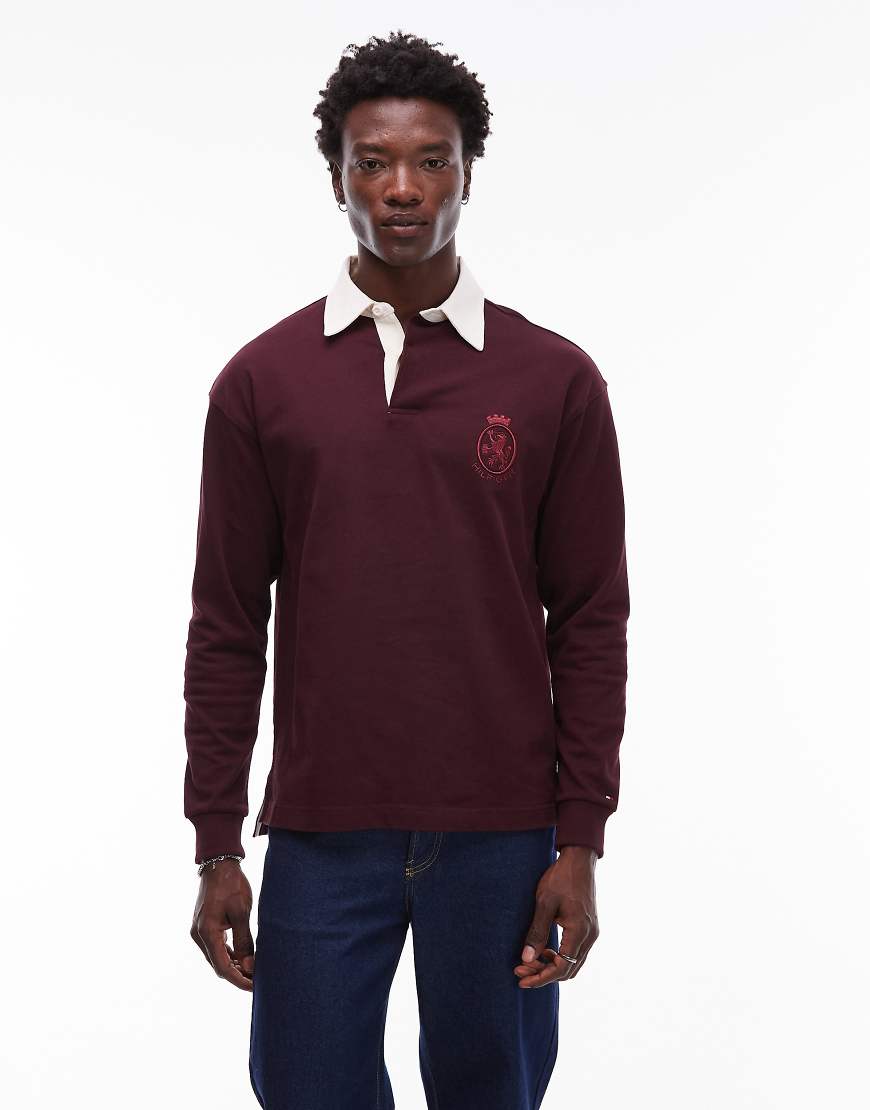 Tommy Hilfiger - Langärmliges Rugby-Polohemd in Burgunderrot mit Wappen-Logo Tommy Hilfiger - Langärmliges Rugby-Polohemd in Burgunderrot mit Wappen-Logo von Tommy Hilfiger