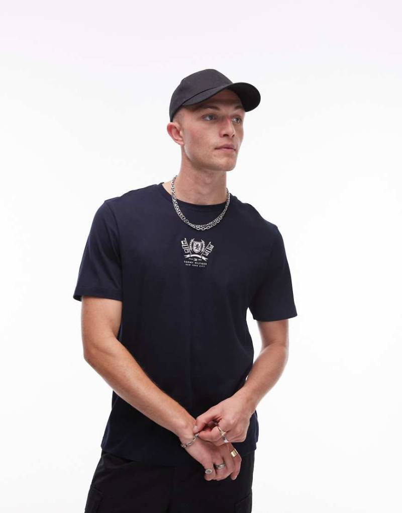 Tommy Hilfiger - T-Shirt in Marineblau mit gesticktem Wappen-Logo Tommy Hilfiger - T-Shirt in Marineblau mit gesticktem Wappen-Logo von Tommy Hilfiger