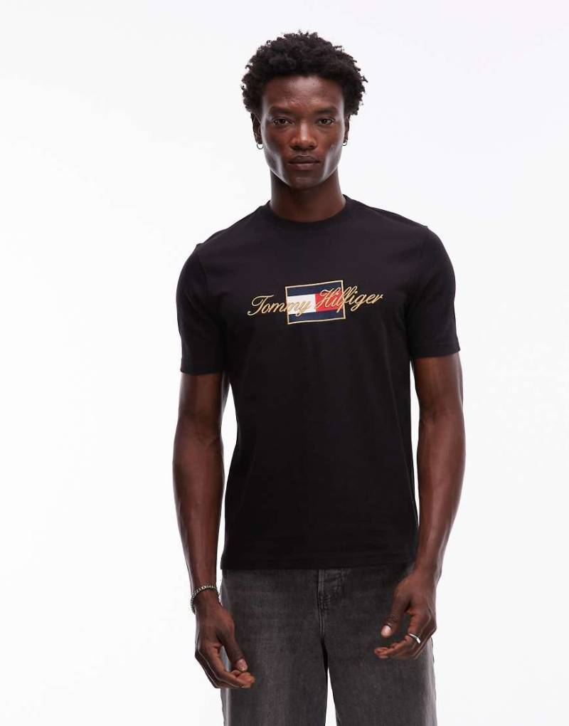 Tommy Hilfiger - T-Shirt in Schwarz mit Flag-Grafik und goldfarbenem Detail von Tommy Hilfiger