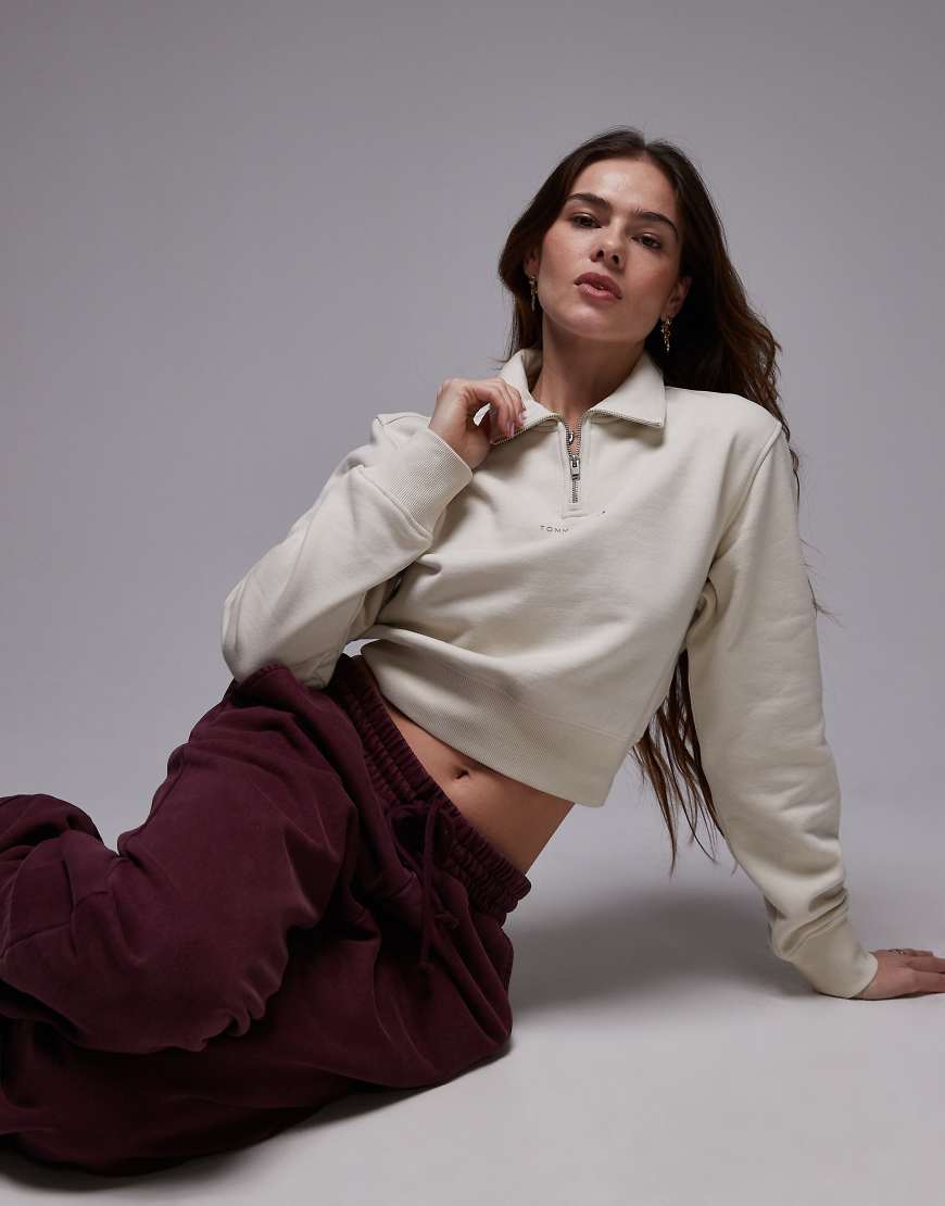 Tommy Jeans - Cropped Sweatshirt in Wollweiß mit kurzem Reißverschluss Tommy Jeans - Cropped Sweatshirt in Wollweiß mit kurzem Reißverschluss von Tommy Jeans