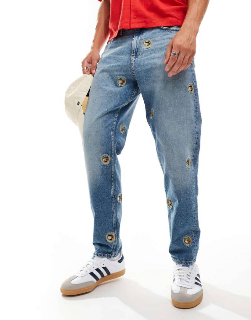 Tommy Jeans - Isaac - Schmal zulaufende Jeans in mittlerer Waschung mit Wappendetails und lockerem Schnitt-Blau von Tommy Jeans