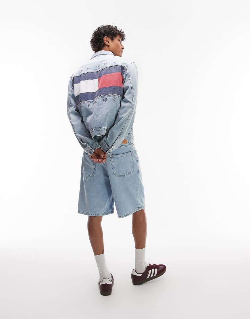 Tommy Jeans - Jeansjacke in hellblauer Waschung mit Vintage-Flaggenprint auf dem Rücken Tommy Jeans - Jeansjacke in hellblauer Waschung mit Vintage-Flaggenprint auf dem Rücken von Tommy Jeans