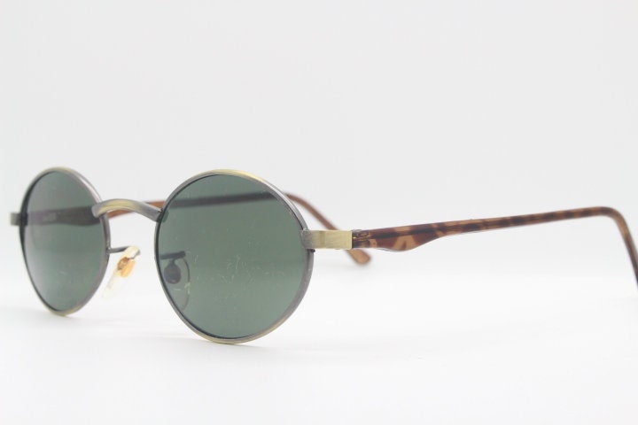 90Er Vintage Ovale Sonnenbrille. Kleine Fassung in Satin Bronze Mit Grünen Gläsern Und Farblich Abgesetzten Bügeln. Unbenutzt Nos. Zustand 90Er Vintage Ovale Sonnenbrille. Kleine Fassung in Satin Bronze Mit Grünen Gläsern Und Farblich Abgesetzten Bügeln. Unbenutzt Nos. Zustand von YouaretheBrandLondon