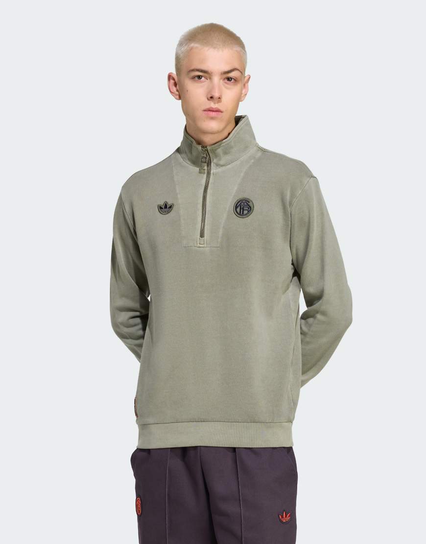 adidas Originals - FC Bayern Terrace Icons - Oberteil in Base-Grün mit kurzem Reißverschluss adidas Originals - FC Bayern Terrace Icons - Oberteil in Base-Grün mit kurzem Reißverschluss von adidas Originals