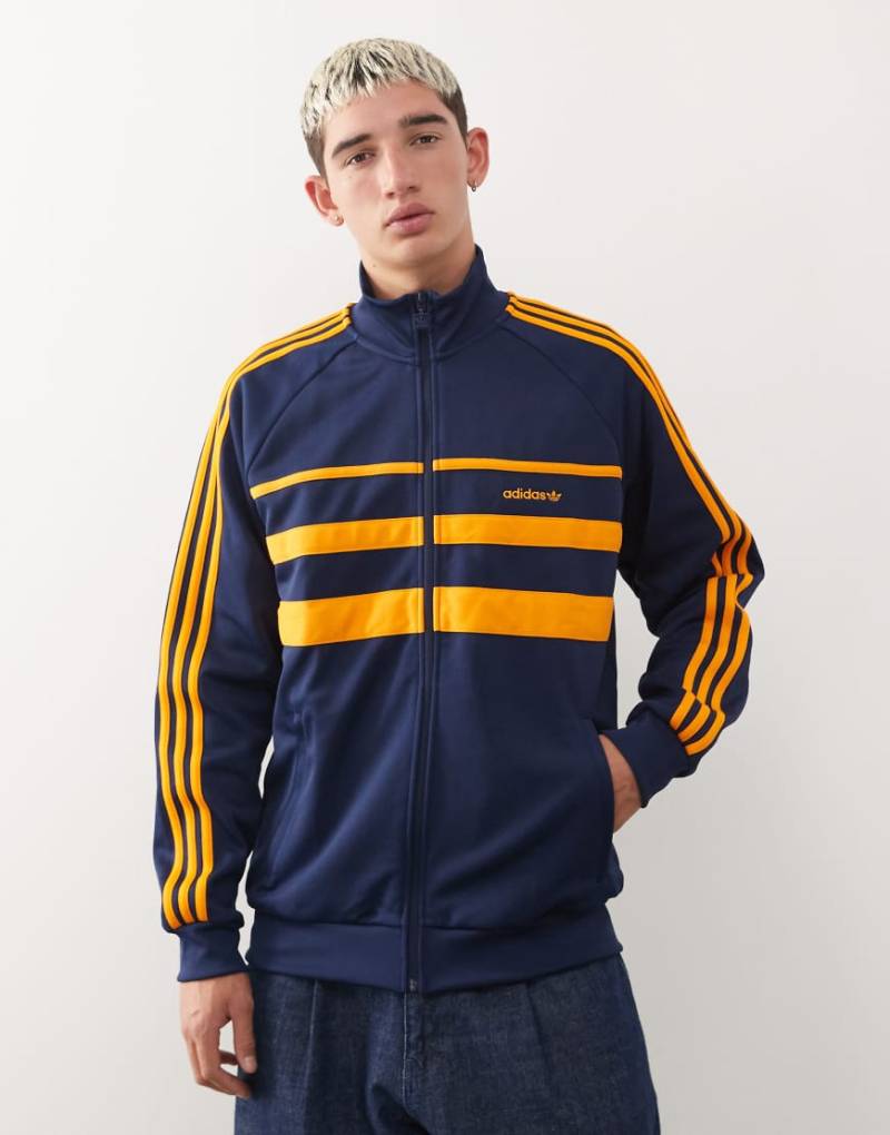 adidas Originals - First - Trainingsoberteil in Marineblau und Orange adidas Originals - First - Trainingsoberteil in Marineblau und Orange von adidas Originals