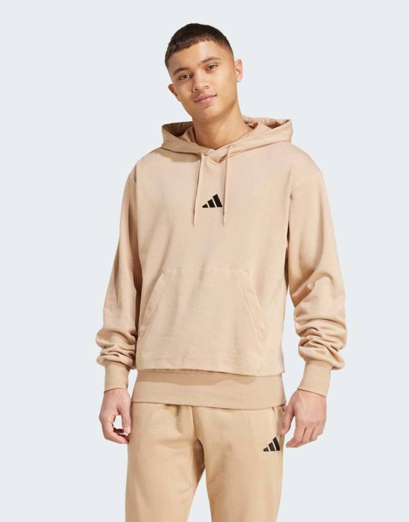 adidas Performance - Essentials - Feelcozy - Kapuzenpullover aus French Terry in Warm Sandstone / Schwarz-Braun von adidas performance