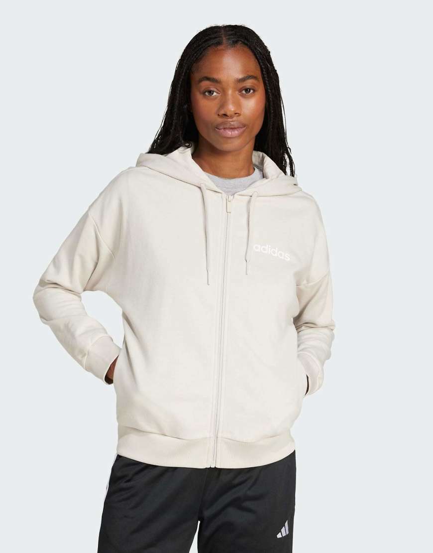 adidas Performance - Essentials - Kapuzenjacke aus Frottee in Beige/Weiß mit linearem Logo und Reißverschluss-Neutral adidas Performance - Essentials - Kapuzenjacke aus Frottee in Beige/Weiß mit linearem Logo und Reißverschluss-Neutral von adidas performance