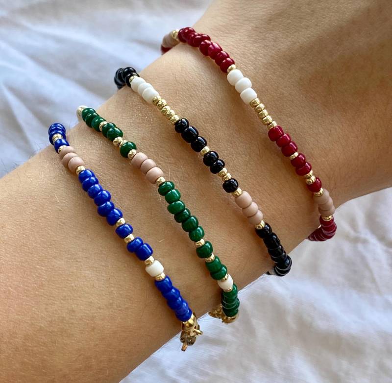 Schlichtes Gefädeltes Abstraktes Armband in Dunklen Farben Mit Goldenen, Weißen Und Beigen Details Schlichtes Gefädeltes Abstraktes Armband in Dunklen Farben Mit Goldenen, Weißen Und Beigen Details von florescerjewelry