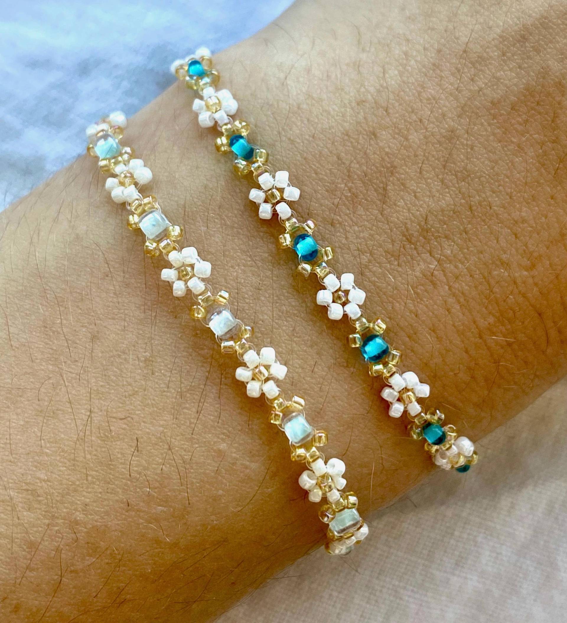 Zartes Elegantes Perlenarmband in Blauen Pastellfarben Mit Kleinen Goldenen Details Und Weißen Gänseblümchen-Blüten Zartes Elegantes Perlenarmband in Blauen Pastellfarben Mit Kleinen Goldenen Details Und Weißen Gänseblümchen-Blüten von florescerjewelry