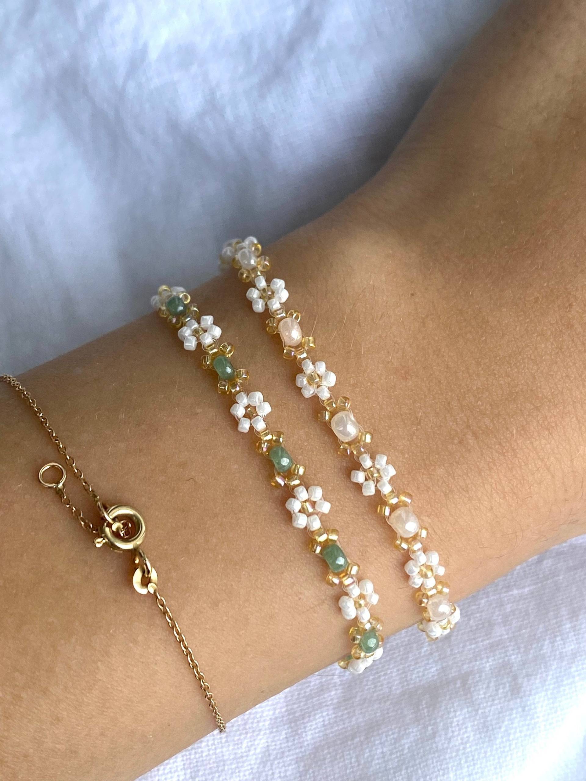 Zartes Elegantes Perlenarmband in Pastellfarben Mit Kleinen Goldenen Details Und Weißen Gänseblümchen-Blüten Zartes Elegantes Perlenarmband in Pastellfarben Mit Kleinen Goldenen Details Und Weißen Gänseblümchen-Blüten von florescerjewelry